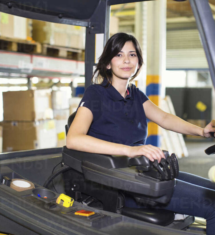 Portrait of female forklift truck driver working in distribution warehouse